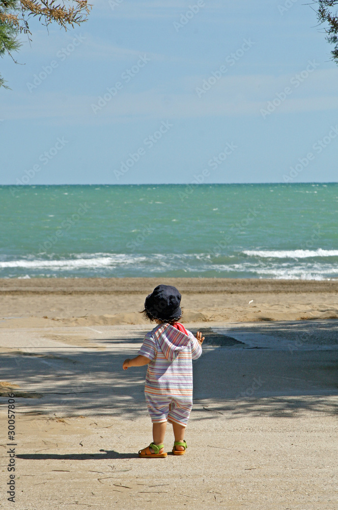 child facing the sea on a summer day