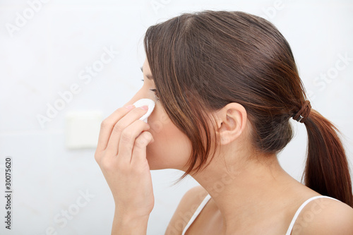 Young beautiful caucasian woman cleaning her face