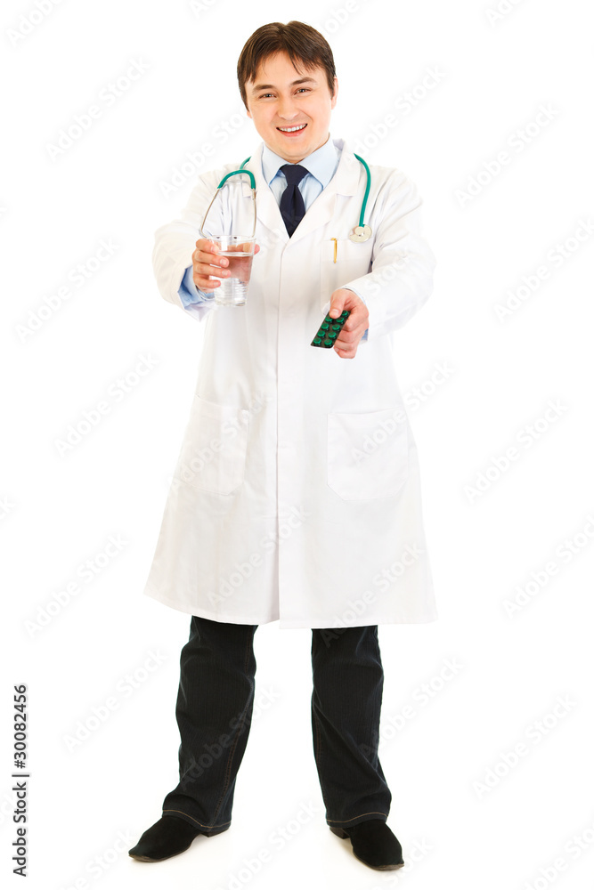 Smiling doctor holding pack of pills and glass of water Smiling doctor holding pack of pills and glass of water