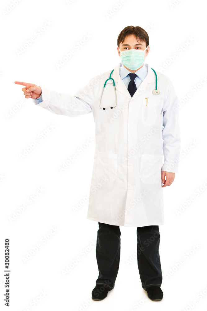 Medical doctor in mask pointing finger at something Medical doctor in mask pointing finger at something