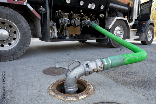 Fuel delivery tanker truck filling up storage tank