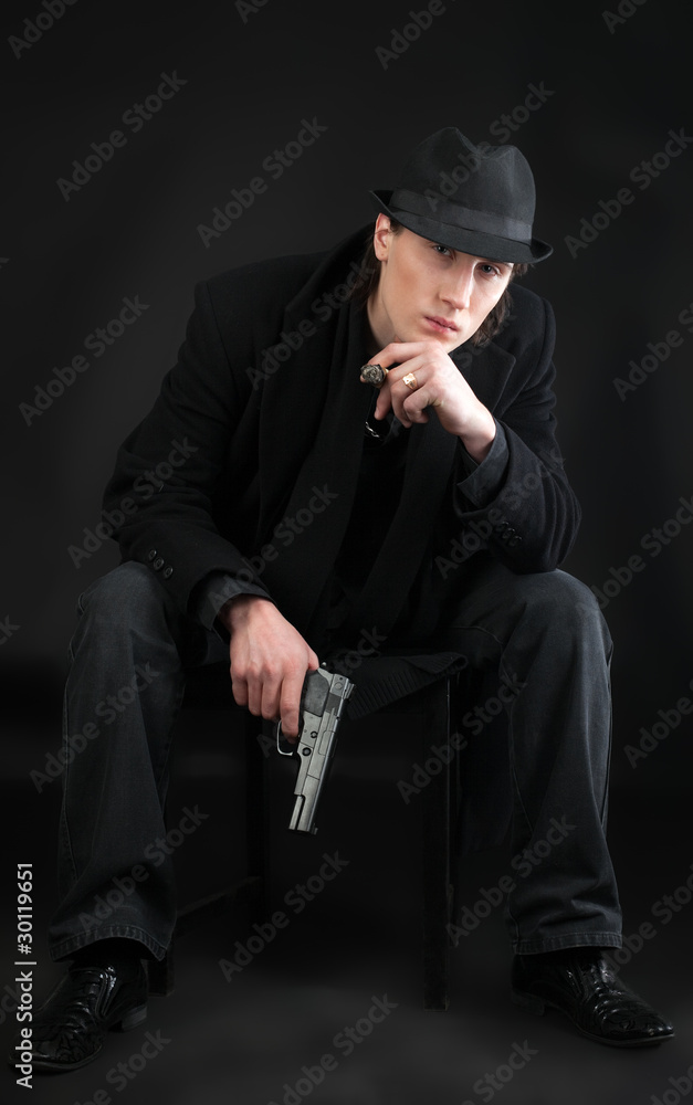 Man with pistol sit in black cloth Man with pistol sit in black cloth