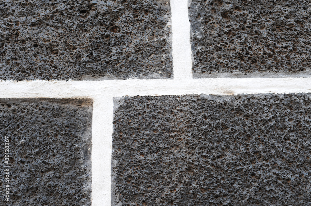 Fototapeta premium Dark volcanic bricks with white cement joints, pattern