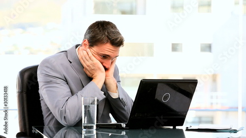 Young businessman despairing in front of his laptop photo