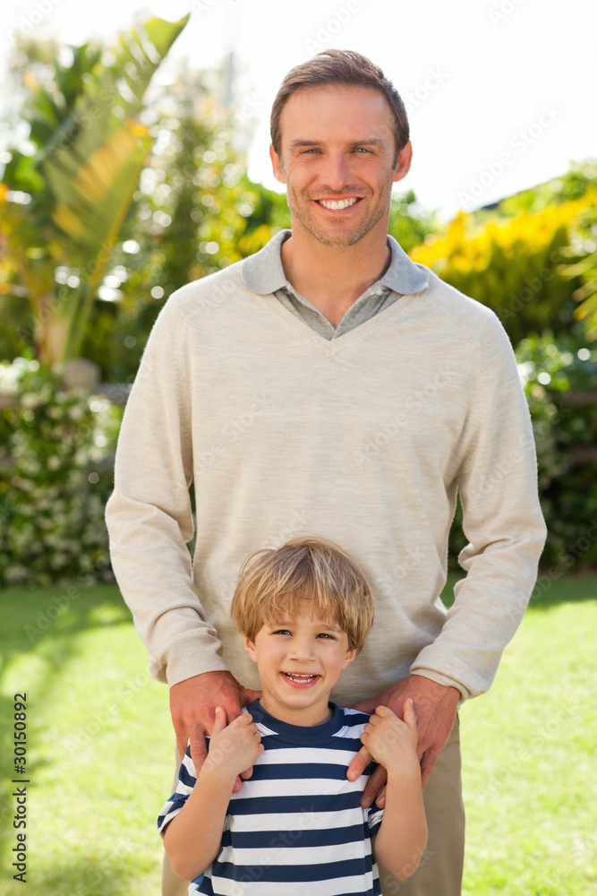 Father and his son looking at the camera in the garden Father and his son looking at the camera in the garden