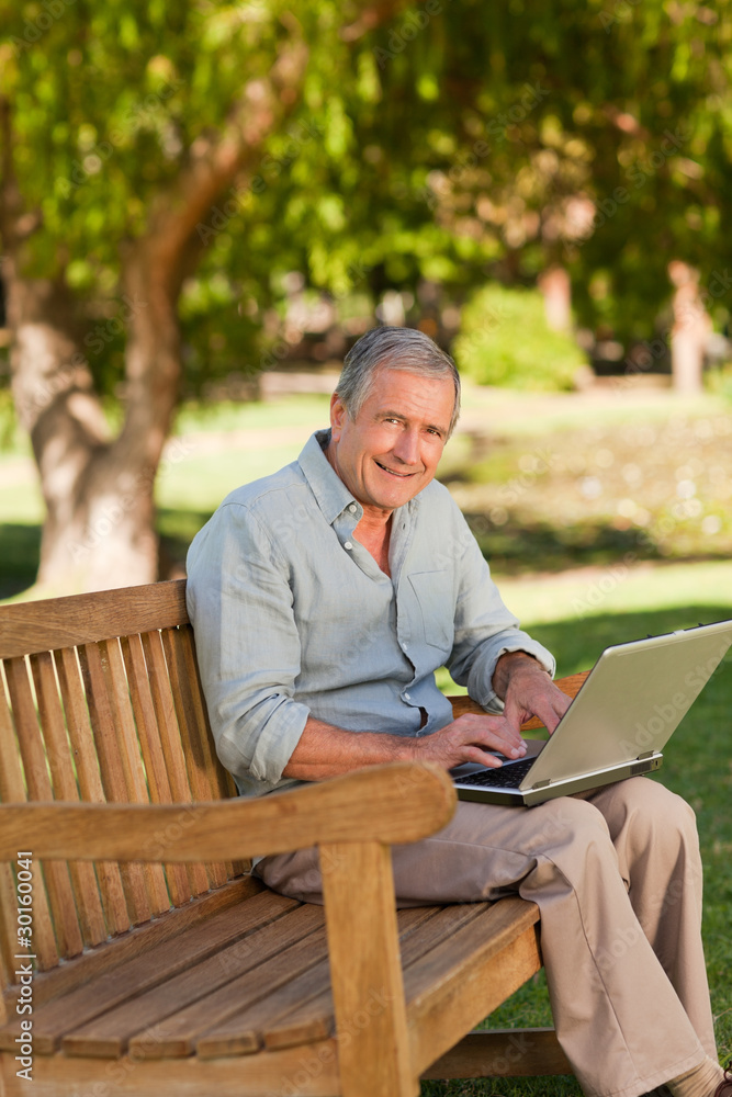 Elderly man working on his laptop in the park Elderly man working on his laptop in the park