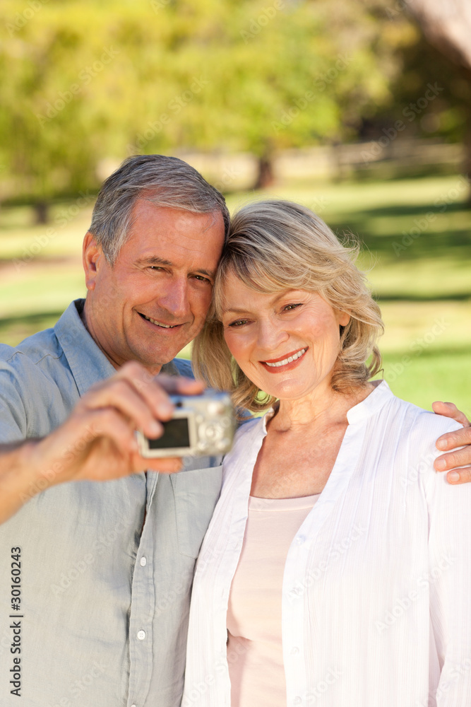 Elderly couple taking a photo of themselves in the park Elderly couple taking a photo of themselves in the park