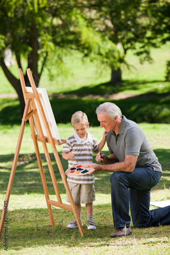 Grandfather and his grandson painting in the garden