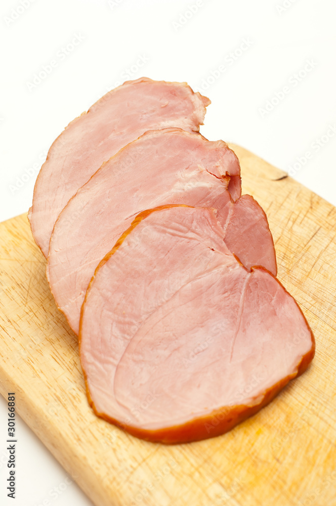 Sliced ham on a wooden board isolated on white background.