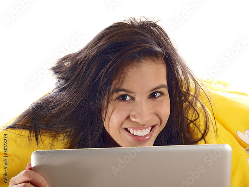 smiling girl lying in bed with a computer notebook