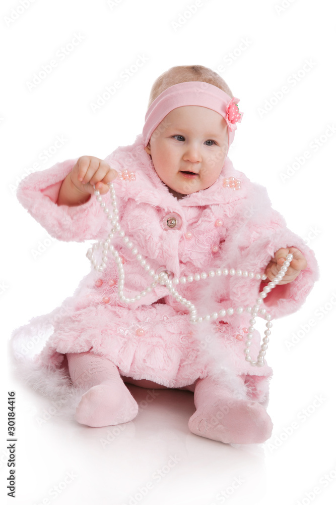 The child in a pink suit with a beads sits on a floor