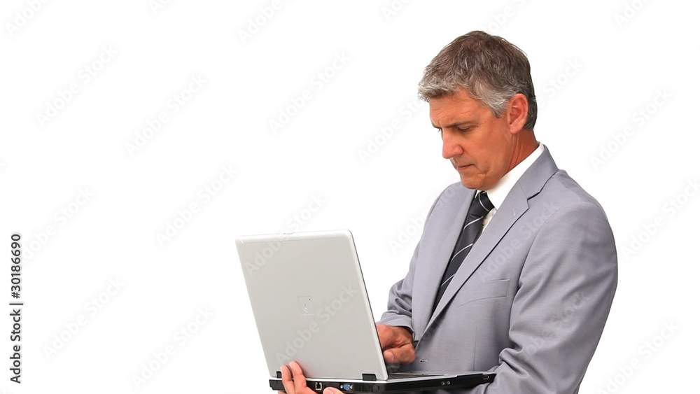 Middle aged man in suit standing with a laptop Middle aged man in suit standing with a laptop