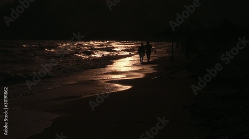 People walk on the beach at sunset
