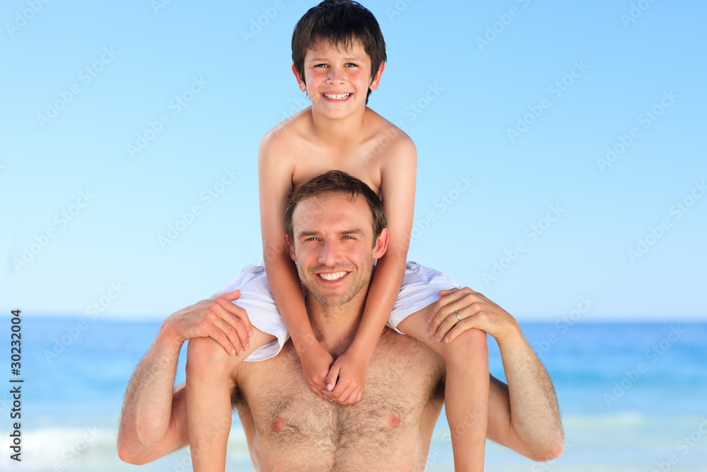 Obraz premium Father having son a piggyback on the beach