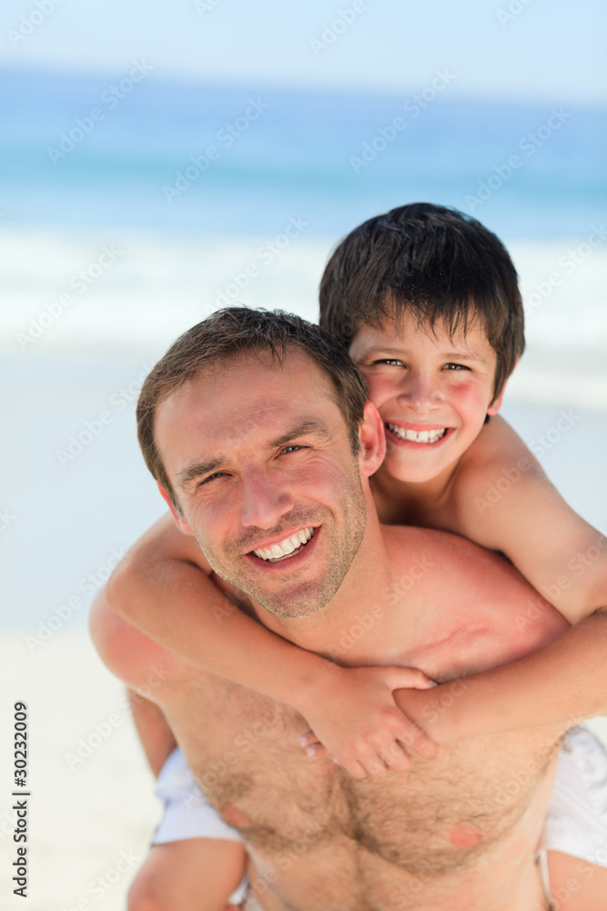Father having son a piggyback on the beach Father having son a piggyback on the beach