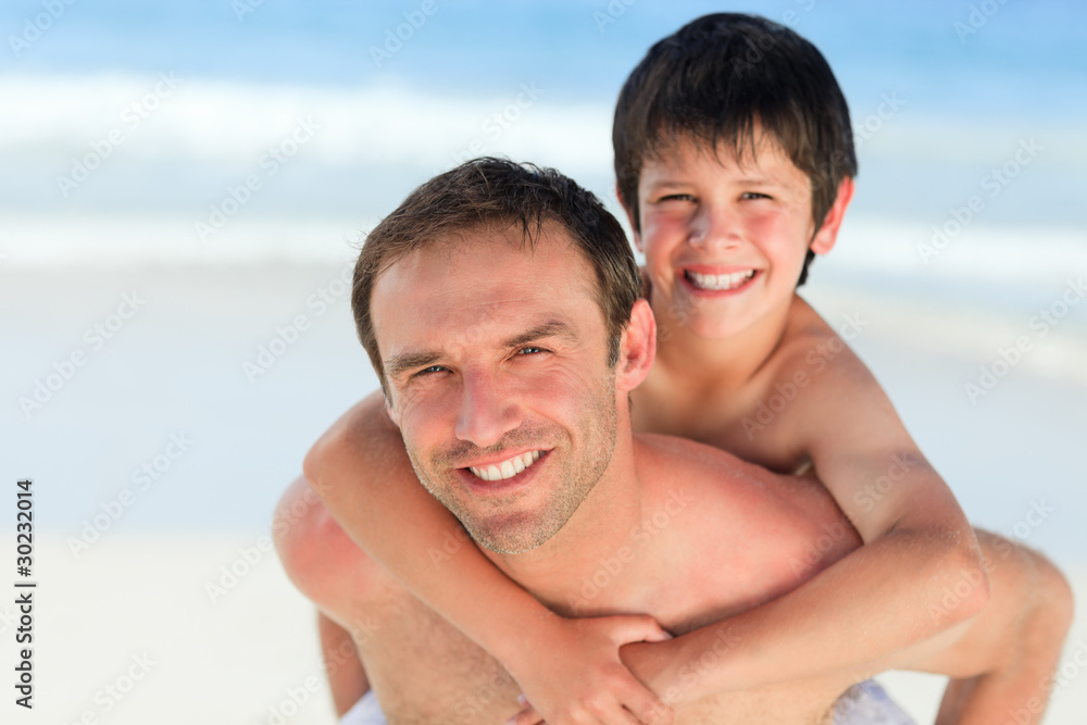 Father having son a piggyback on the beach Father having son a piggyback on the beach
