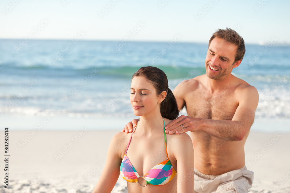 Happy man applying sun cream on his girlfriend's back