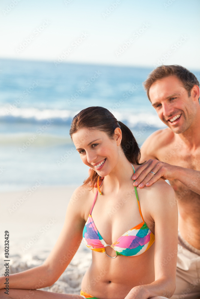 Happy man applying sun cream on his girlfriend's back Happy man applying sun cream on his girlfriend's back