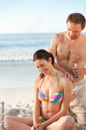Man applying sun cream on his girlfriend's back