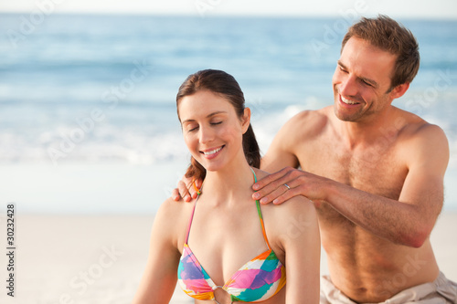Happy man applying sun cream on his girlfriend's back