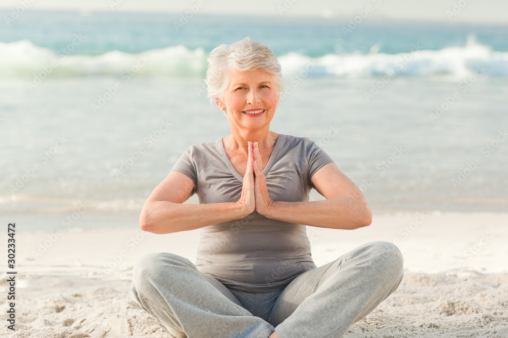 Senior woman practicing yoga on the beach
