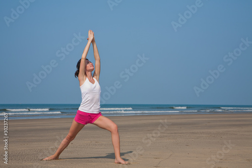 Young woman doing yoga on the beach