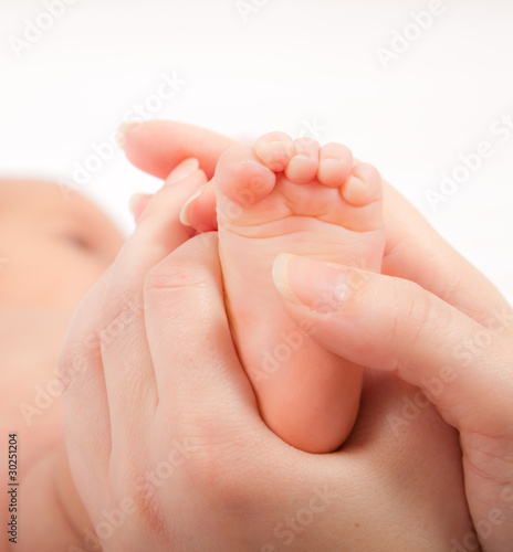 Mother's hands massaging little baby's foot