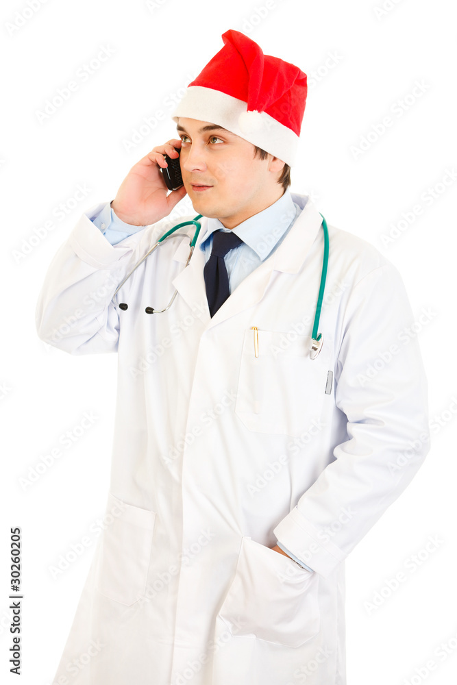 Smiling doctor in hat of Santa Claus talking on mobile phone Smiling doctor in hat of Santa Claus talking on mobile phone