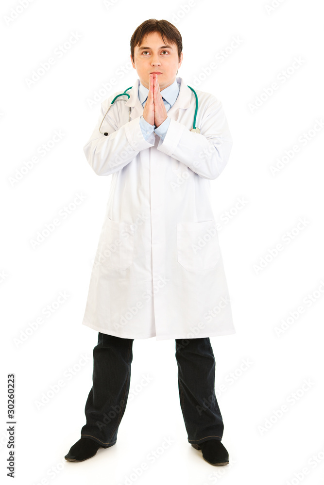 Young medical doctor praying for success isolated on white. Young medical doctor praying for success isolated on white.