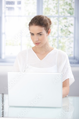 Attractive girl working at home using laptop