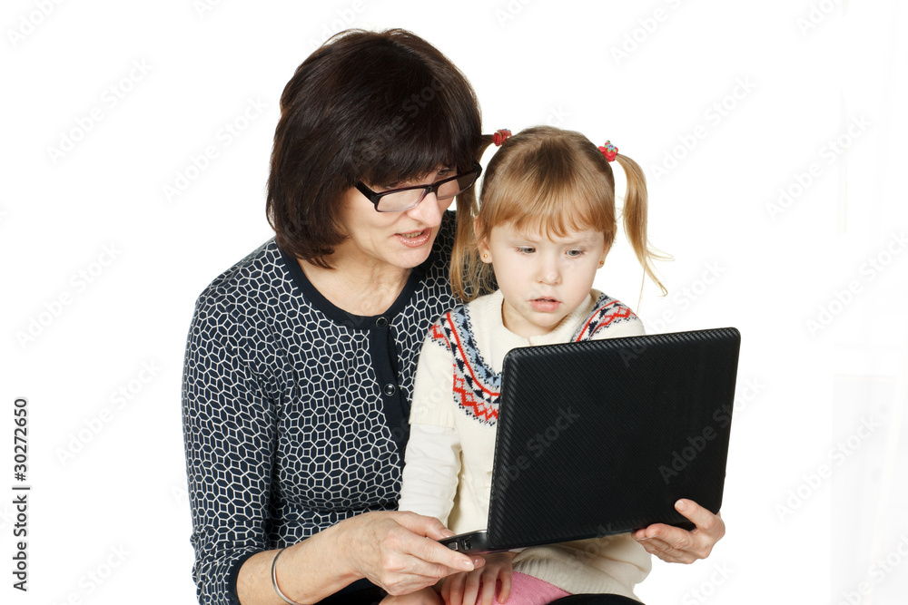 Grandmother demonstrating her granddaughter smth in laptop