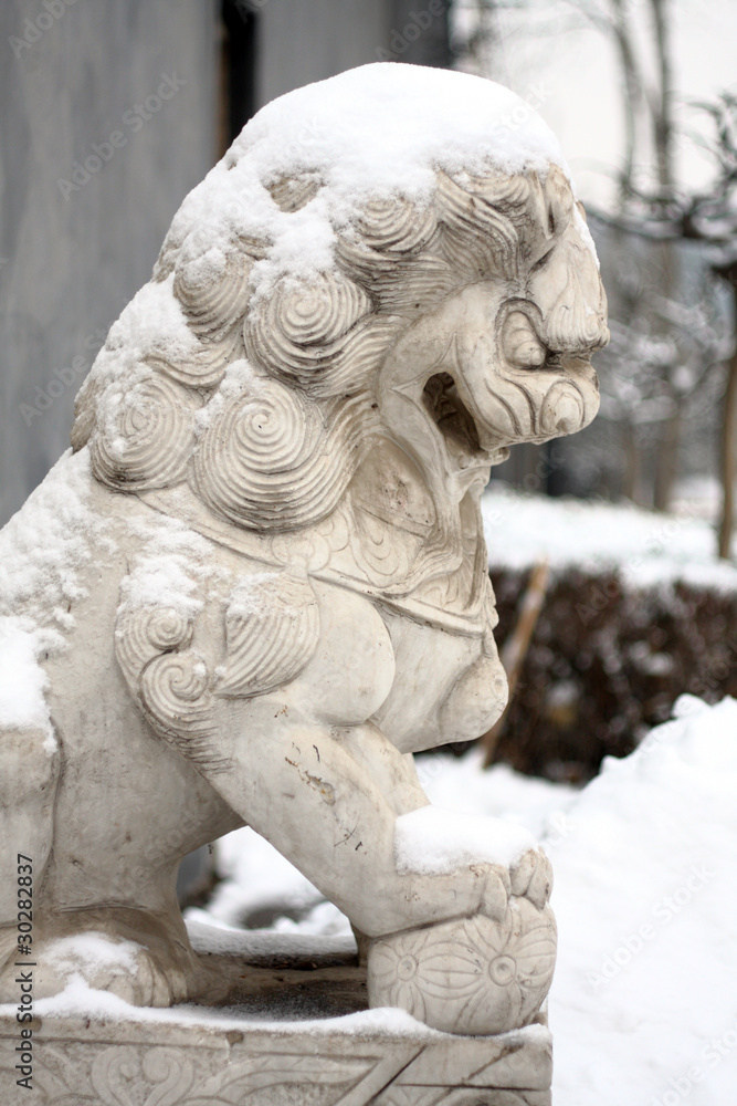 marble lion covered by snow in winter