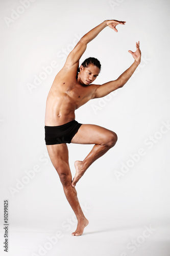 young male dancer posing over grey background