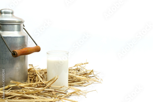 Milchkanne und Glas auf Stroh