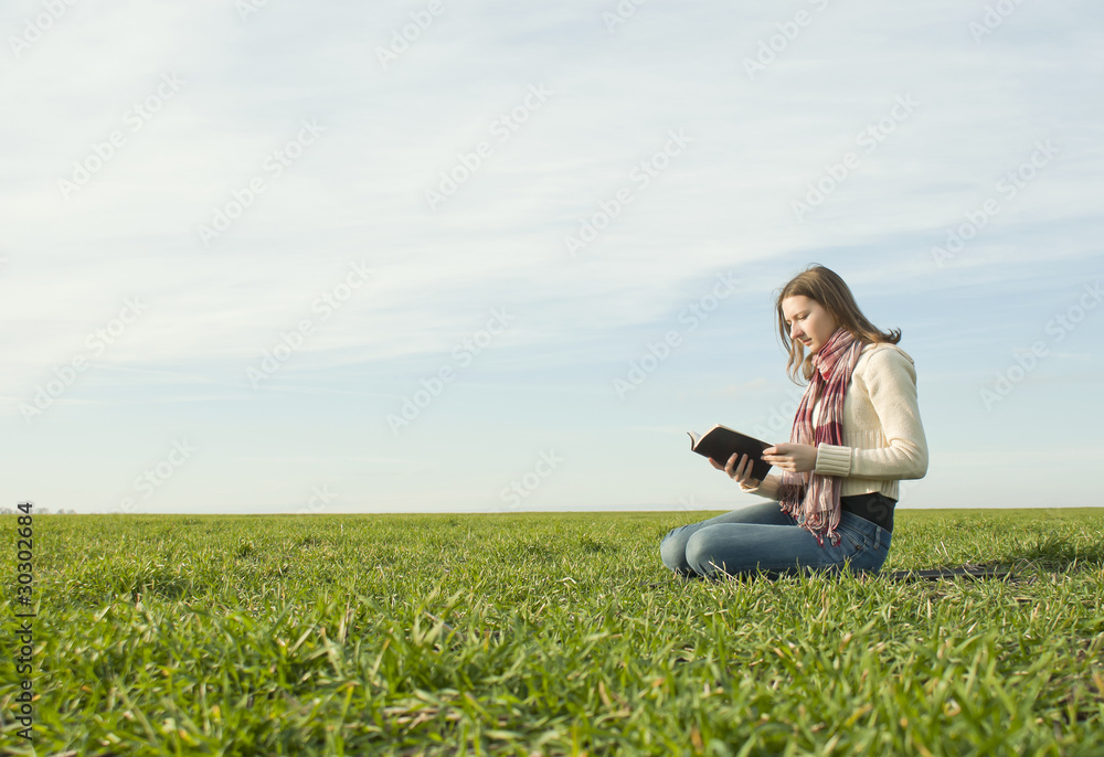 Girl reading a book sitting at grass