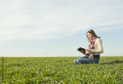 Girl reading a book sitting at grass © andreykr