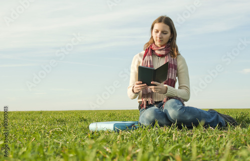 Girl reading a ebook sitting at grass