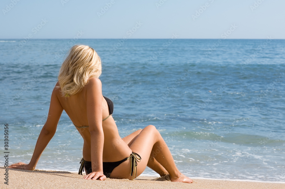 Attractive girl sitting on the sand beside the sea Attractive girl sitting on the sand beside the sea