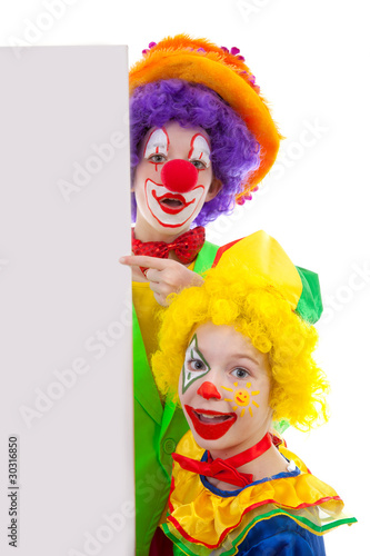 Two girl clowns holding empty text board over white background photo