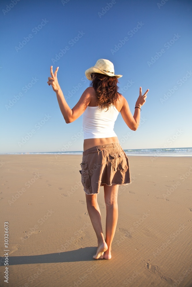 winner woman with hat walking at beach