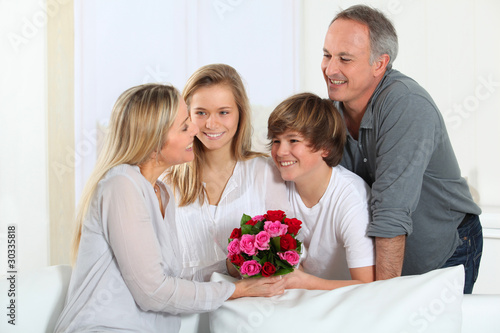 Father and children offering bunch of flowers on mother's day