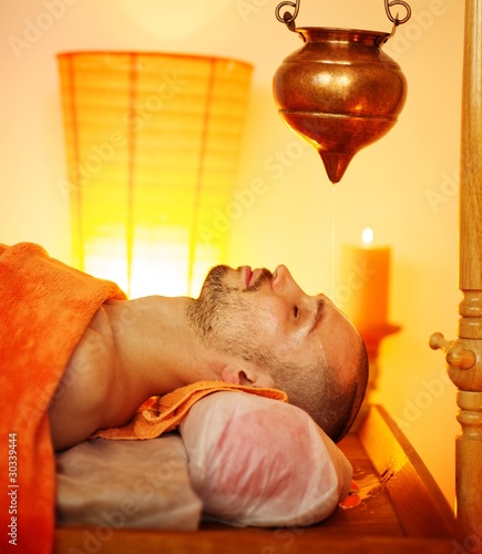 Man having a shirodhara massage in a salon photo