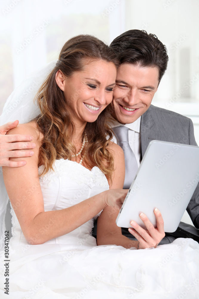 Bride and groom using electronic tablet Bride and groom using electronic tablet