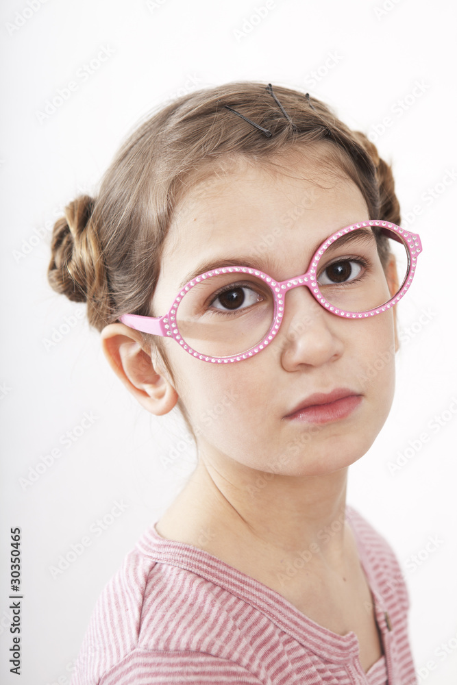 portrait of serious little girl nine years old in pink glasses