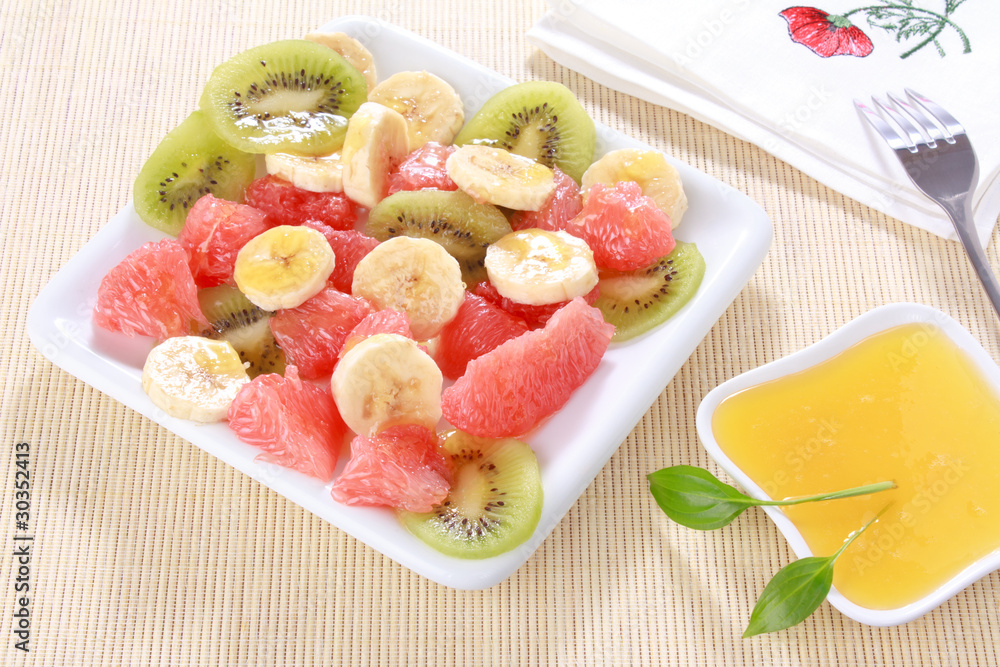 Fresh fruits salad on white plate with honey