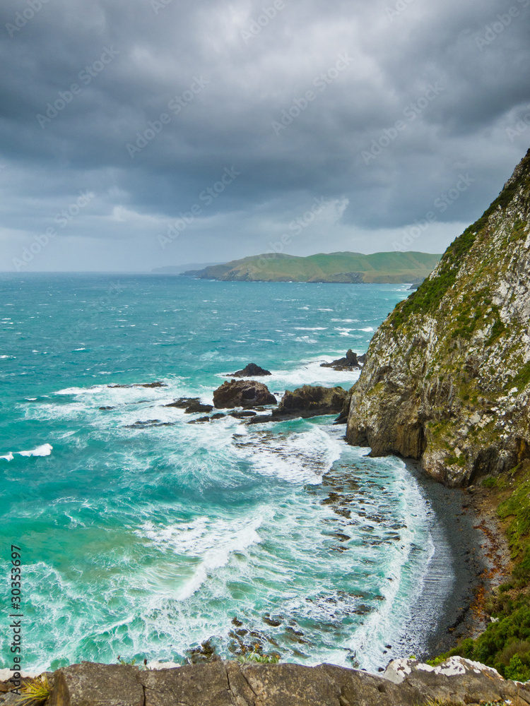 Cliffs under thunder clouds and turquoise ocean