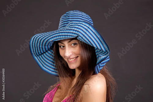 Pretty young smiling girl in hat on dark