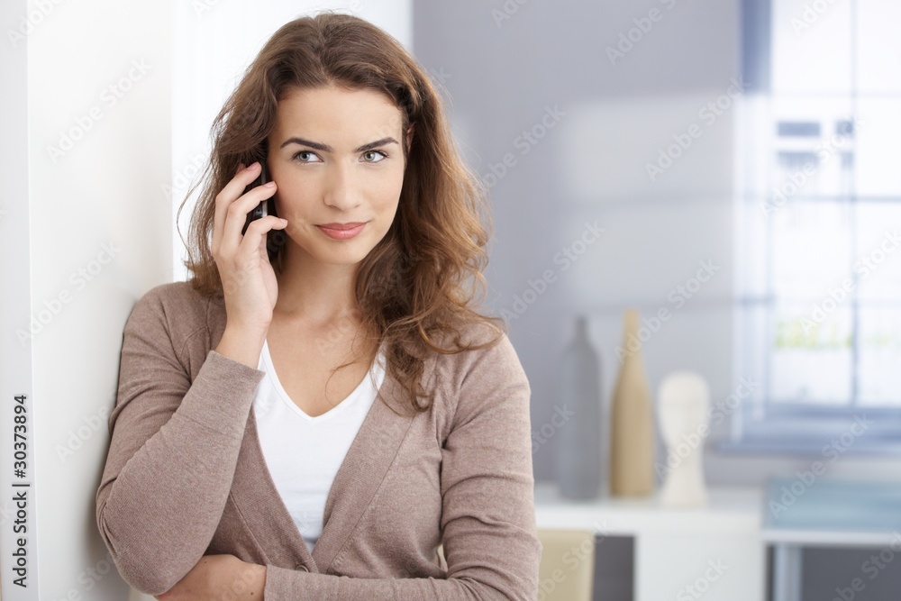 Young woman talking on mobile in living room Young woman talking on mobile in living room