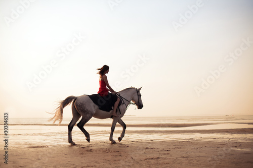 Girl riding a horse on the background of the sea