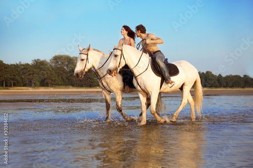 Fototapeta Naklejka Na Ścianę i Meble -  Young couple in the sea on horseback